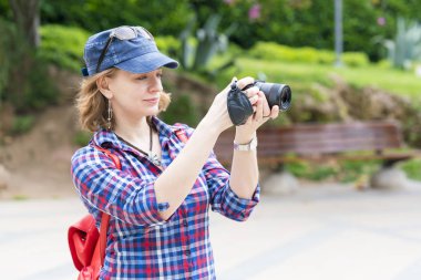 Kameraya bakarak bir sırt çantası ile kırmızı şapkalı kadın