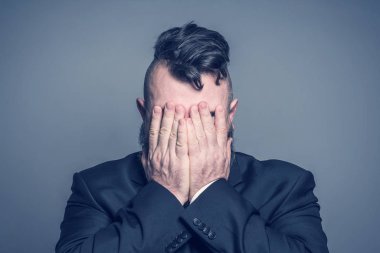 Yetişkin adam bir takım elbise ve bir mohawk saç modeli gri bir arka yüzünde kaplı