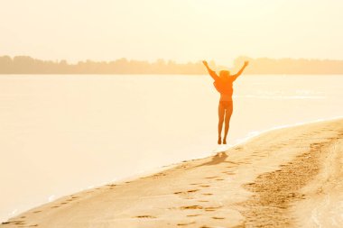 Sarışın genç güneş altında sahilde kadar atlama