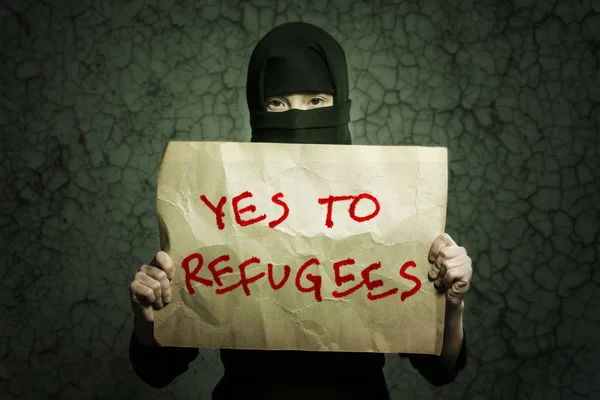 身穿黑色头巾的穆斯林女孩拿着一张海报 上面写着 在背景墙上有裂缝 — 图库照片