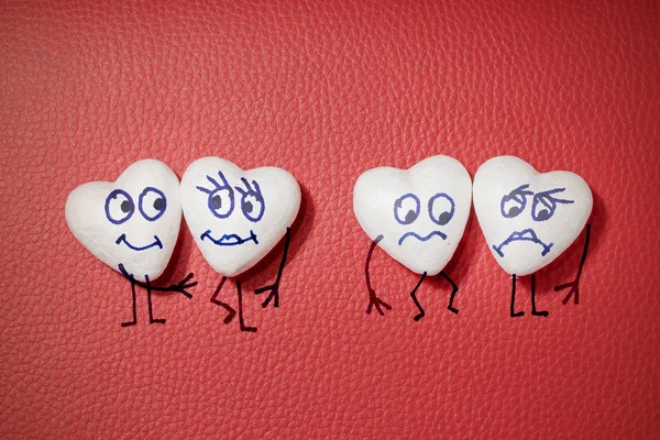 Four white hearts with faces on red leather background