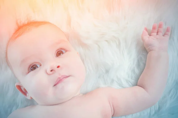Niedliches Baby Liegt Auf Weißem Fell Sonnenlicht — Stockfoto
