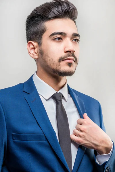 Young attractive man in a blue suit on a gray background. Isolated