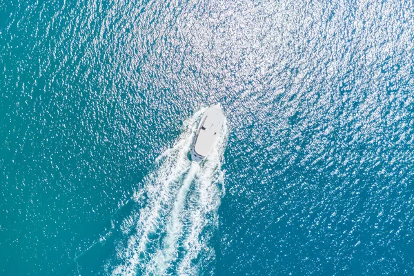 Top view of a white boat sailing in the blue sea on a sunny day