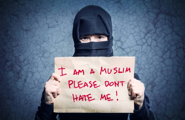 碑文とポスターを持って黒のヒジャーブのイスラム教徒の少女よ イスラム嫌いしないでくださいと壁の背景に私私の亀裂します — ストック写真