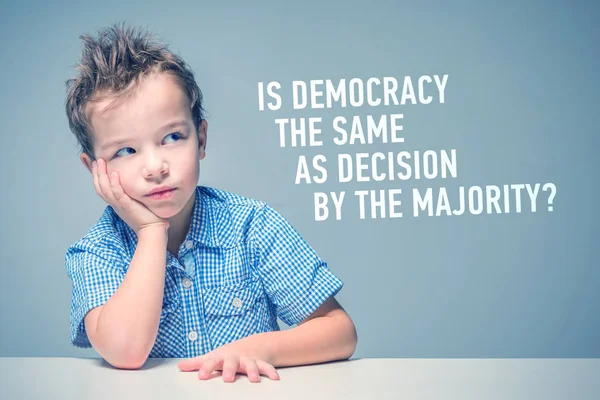 碑文の横にあるテーブルに座って青いシャツの少年は 民主主義は大多数の決定と同じですか — ストック写真