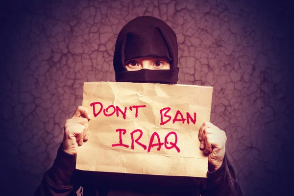 身穿黑色头巾的穆斯林女孩拿着一张写着铭文的海报不要禁止伊拉克在背景墙上有裂缝 — 图库照片
