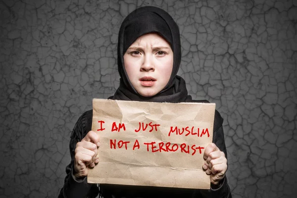 私は午前だけイスラム教徒いない テロリストの背景には亀裂の壁の碑文でポスターを保持している黒のヒジャーブのイスラム教徒の少女 — ストック写真