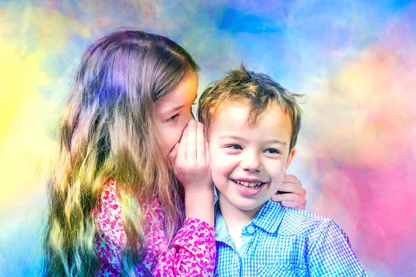 Girl in a red dress whispers in the ear a boy in a blue shirt on a multicolor background