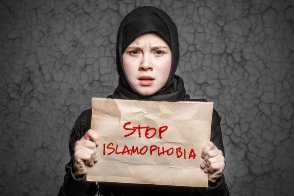 碑文とポスターを持って黒のヒジャーブのイスラム教徒の少女を停止恐怖症と背景の壁に亀裂します — ストック写真