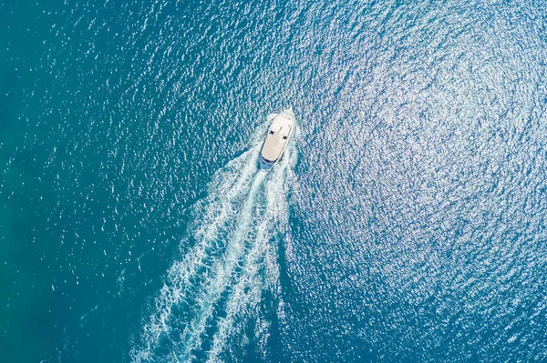 Top view of a white boat sailing in the blue sea