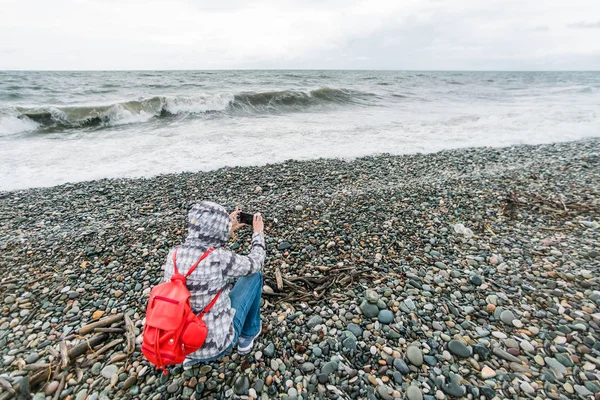 Kobieta Czerwony Plecak Fotografowanie Morza Kamienistej Plaży — Zdjęcie stockowe