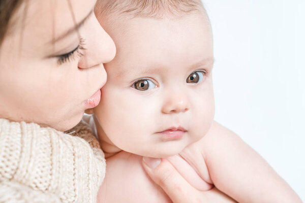 Mother kissing crying baby on a white background