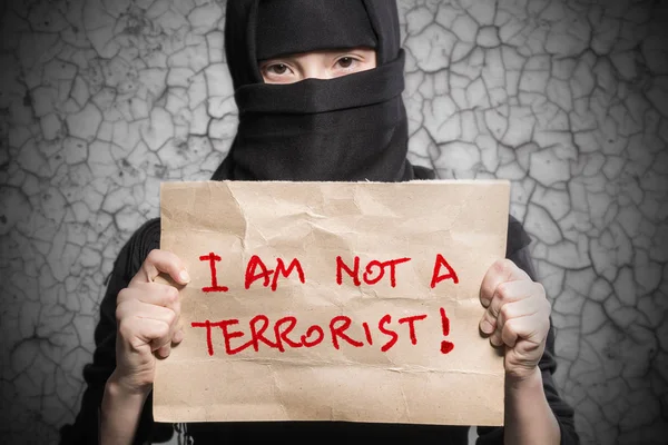 私午前ない テロリストの背景に壁の亀裂の碑文とポスターを持って黒のヒジャーブのイスラム教徒の少女 — ストック写真