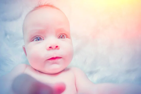太陽の下で白い毛皮に横たわっているかわいい赤ちゃん — ストック写真