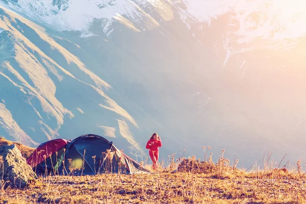 Woman in a red jacket near a tourist tent in the mountains