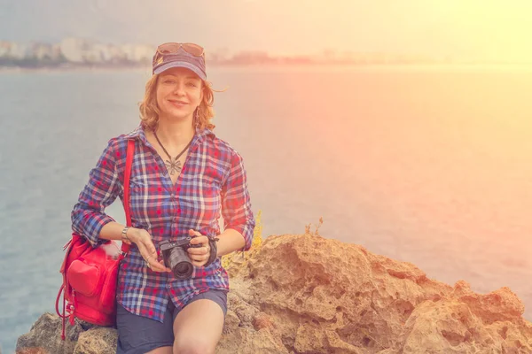 Женщина Шляпе Красным Рюкзаком Камерой Сидящей Скале Моря Солнце — стоковое фото