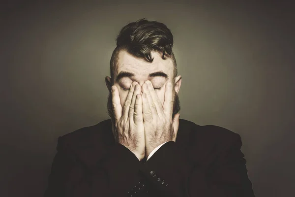 Adult bearded man in a suit covers her face