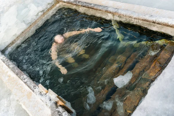 Man dive into an ice hole  in the feast Epiphany