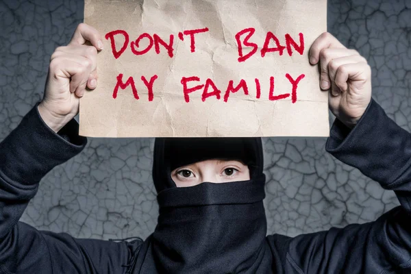穆斯林女孩在黑色头巾拿着一张海报与题词不要禁止我的家人对一堵墙与裂缝 — 图库照片