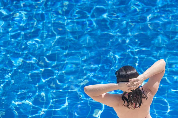 青い水プールの背景にブルネットの女性 — ストック写真