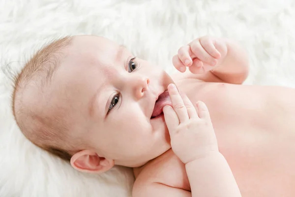 Niedliches Baby Liegt Auf Weißem Flauschigem Hintergrund Und Zeigt Zunge — Stockfoto
