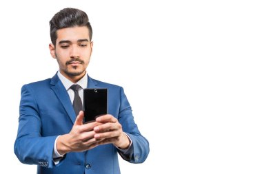 Beyaz bir arka plan üzerinde telefonun ekranına bakarak mavi elbiseli Genç çekici adam. İzole
