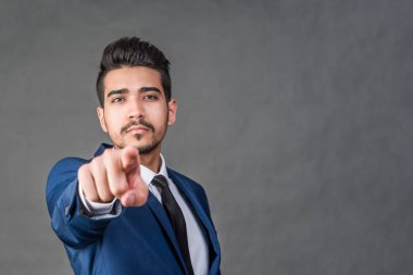 Bir parmak ileri gri bir arka plan üzerinde gösterilen mavi elbiseli Genç çekici adam