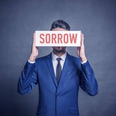 Gri bir arka plan üzerinde kırmızı yazıt üzüntü ile beyaz bir işaret tutan mavi elbiseli Genç çekici adam. Tonda