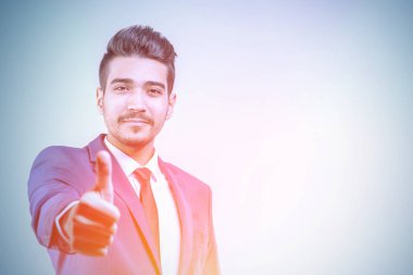 Parlak ışıkta başparmak gösterilmesini mavi elbiseli Genç çekici adam