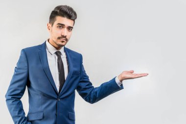Bir mavi elbise yapma jest ile genç çekici adam gri bir arka plan üzerinde eller. İzole