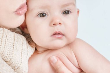 Beyaz bir arka plan üzerinde bir bebek tutan genç kadın