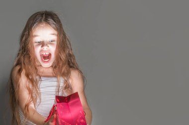 Gri bir arka plan üzerinde kırmızı parlayan Hediyelik çanta içinde korkmuş bir kız görünüyor