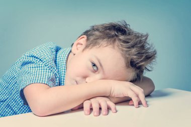 Mavi gömlekli masadaki sevimli çocuk 