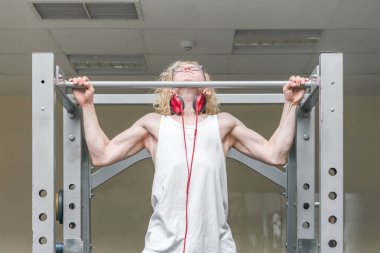 Spor salonunda beyaz yelek kırmızı kulaklık ile zayıf kıvırcık sarışın adam nişanlı