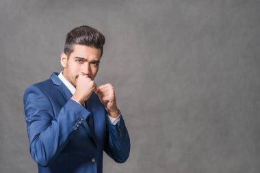 Gri bir arka plan üzerinde mücadele bir duruş ayakta mavi elbiseli Genç çekici adam
