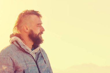 Güneşli bir gün, bir ceketli bir mohawk saç kesimi olan sakallı bir adam portresi