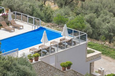 Şemsiyelerle çatıda havuz kenarında şezlong