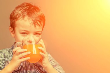 Mavi gömlekli şirin küçük çocuk içecekler portakal suyu güneş ışığında