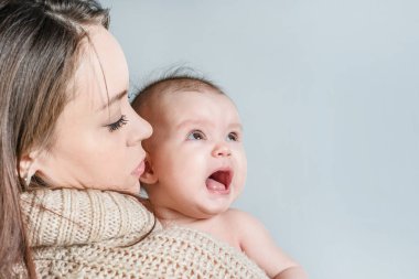 Bir kazak kadında ağlayan bir bebeğin onun kollarında tutar.