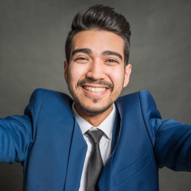 Gri bir arka plan üzerinde mavi elbiseli Genç çekici adam gülümseyen