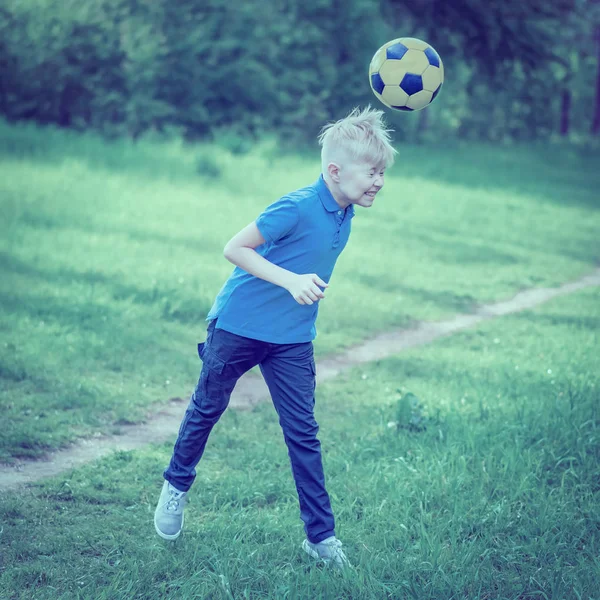 Boy beats his head a soccer ball in the park. Toned