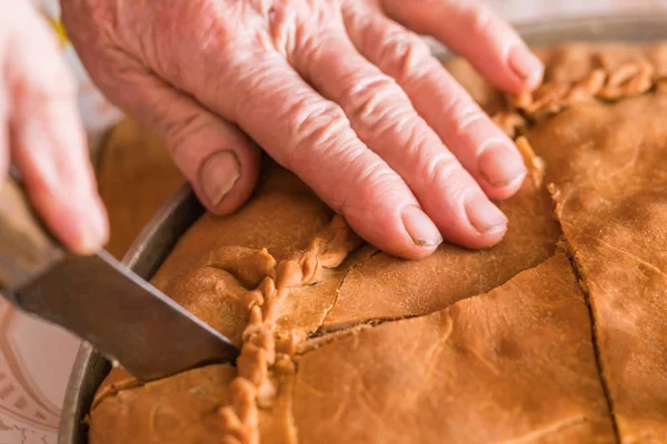 Female hand cuts the cake filled with meat and potatoes - belish