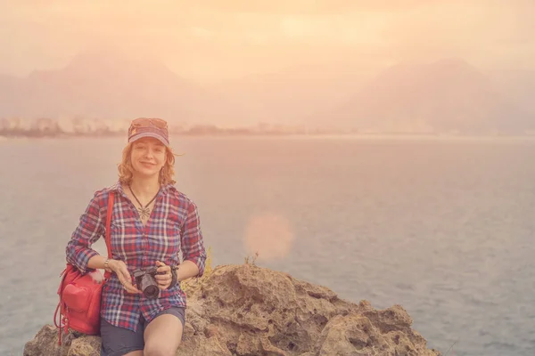 Женщина Шляпе Красным Рюкзаком Камерой Сидящей Скале Моря Солнце — стоковое фото