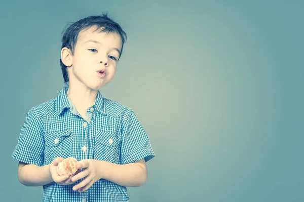 Lindo Niño Con Una Camisa Azul Comiendo Mandarina Tonificado — Foto de Stock