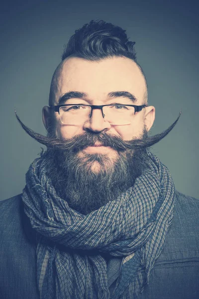 Adult bearded man in a scarf and glasses with long mustache. Toned