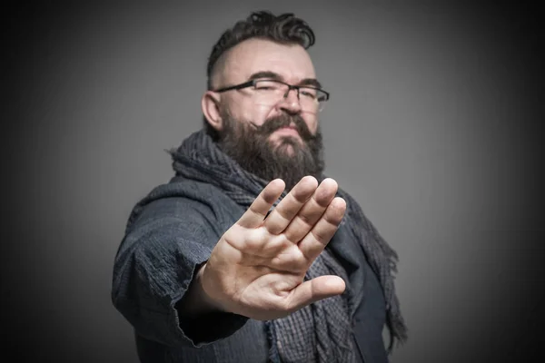 Adult bearded man with a mohawk hairstyle showing hands gesture stop. Toned