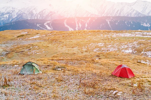 Red and green tourist tents in the mountains at sunny day