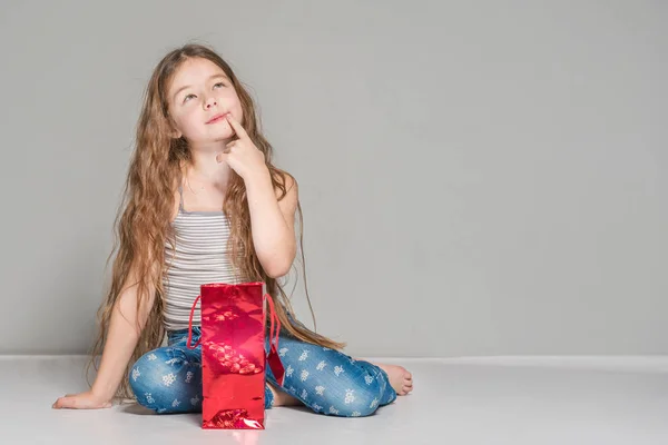 Chica Pensativa Sentada Cerca Una Bolsa Regalo Roja —  Fotos de Stock