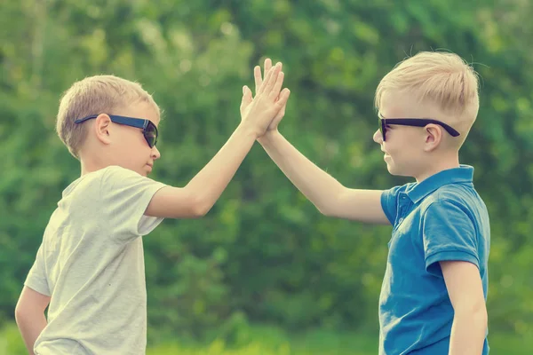 Two boys in sunglasses give five hands in the park